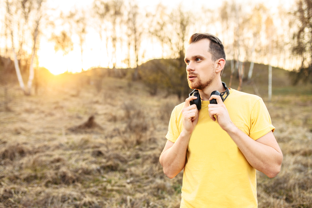 athletic guy with headphones walking outdoors as part his oxygen environment addiction therapy