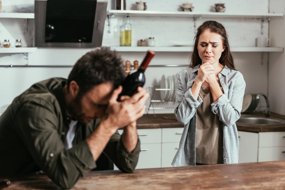 wife looking at her alcoholic husband and praying that he will go to rehab already 