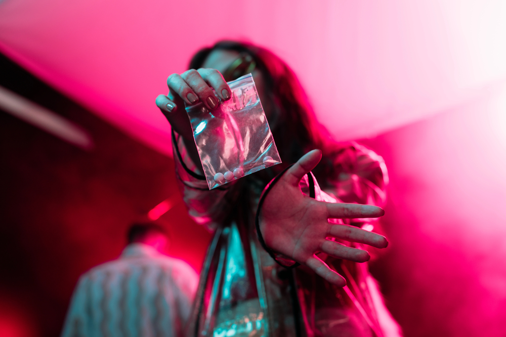 intoxicated woman holding gateway drugs or party drugs at a club