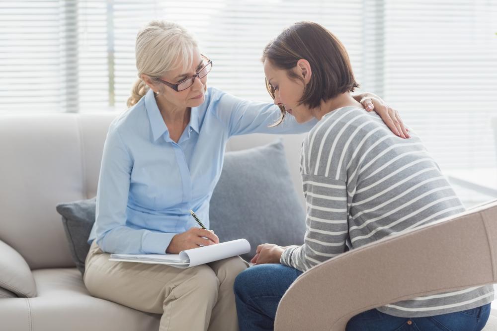 A therapist comforting a woman who is suffering from mental health problem