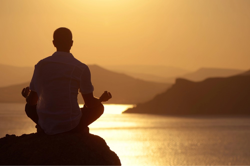a silhouette of a man in yoga post during dusk 