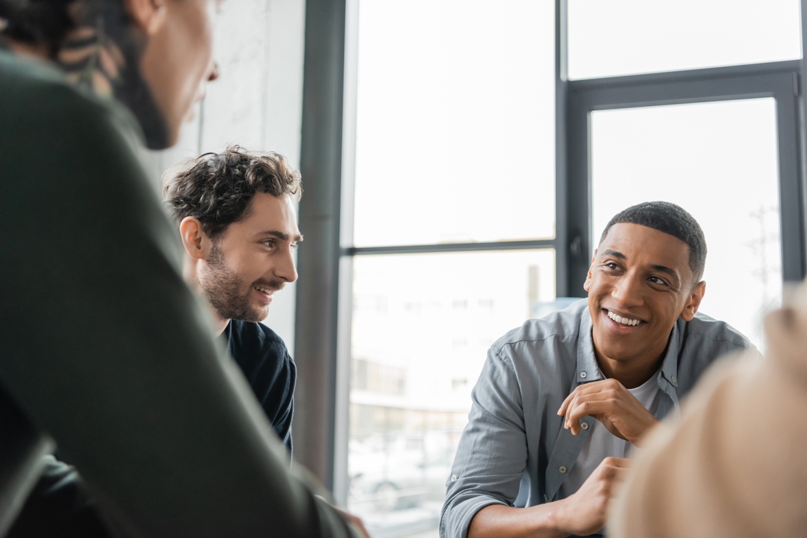 Positive people with alcohol addiction talking during group therapy in rehab cente