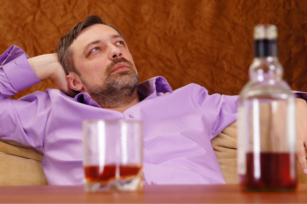 Picture of a man with alcohol on the table