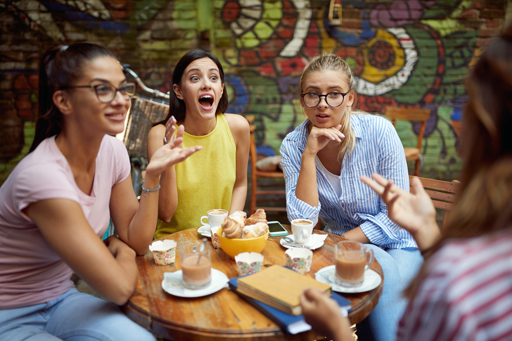 A group of female students is chatting and having a coffee in a pleasant atmosphere at a bar. Leisure, bar, outdoor, friendship