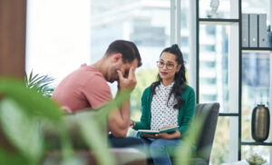 Shot of a young man crying while having a discussion with a woman in a modern office.