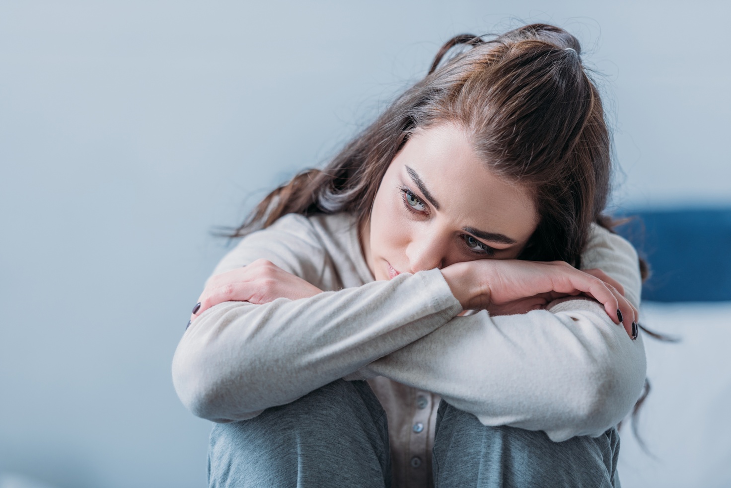depressed woman hugging knees and looking away