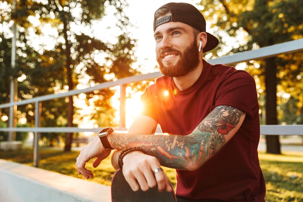 how-long-does-adderall-stay-in-your-system Happy young man with tattoos and ear pods listening to music in a stadium.